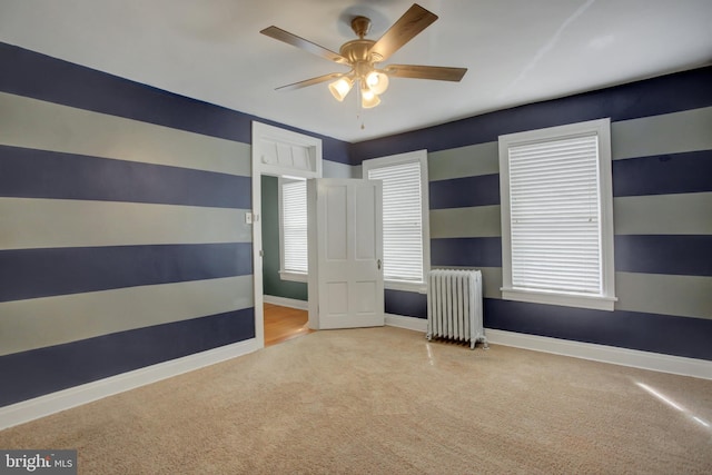 unfurnished bedroom with a ceiling fan, radiator, light carpet, and baseboards