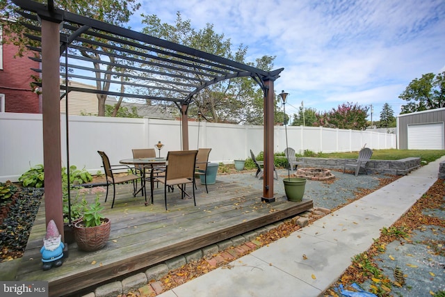 wooden terrace featuring a fenced backyard, a fire pit, a pergola, and outdoor dining space