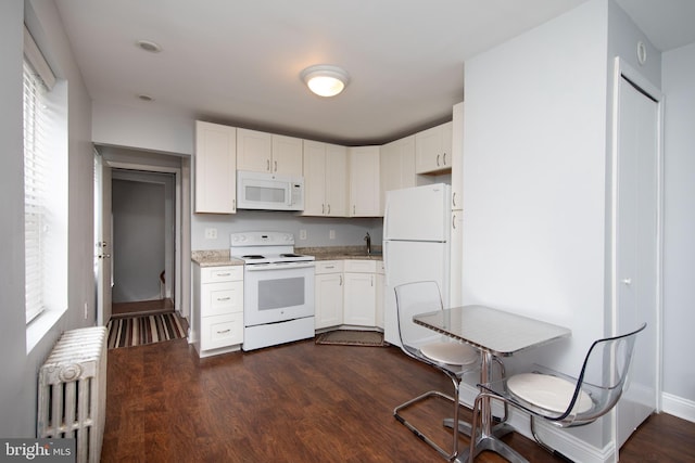 kitchen featuring dark hardwood / wood-style flooring, radiator heating unit, a healthy amount of sunlight, and white appliances