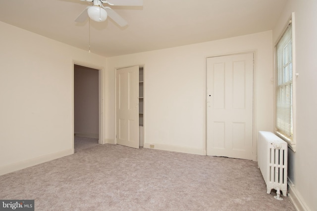 interior space featuring ceiling fan, radiator, and light carpet