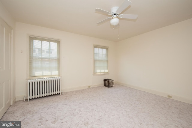 empty room with ceiling fan, light carpet, and radiator