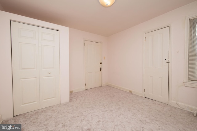 unfurnished bedroom with two closets and light carpet