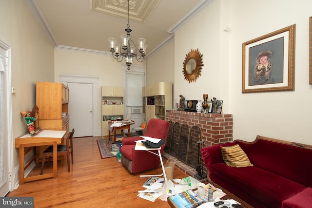 living room featuring wood-type flooring, ornamental molding, a brick fireplace, and an inviting chandelier