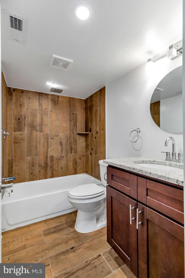 full bathroom featuring hardwood / wood-style floors, vanity, wooden walls, bathing tub / shower combination, and toilet