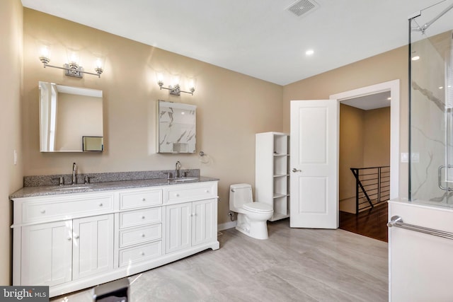 bathroom with hardwood / wood-style flooring, double sink vanity, walk in shower, and toilet