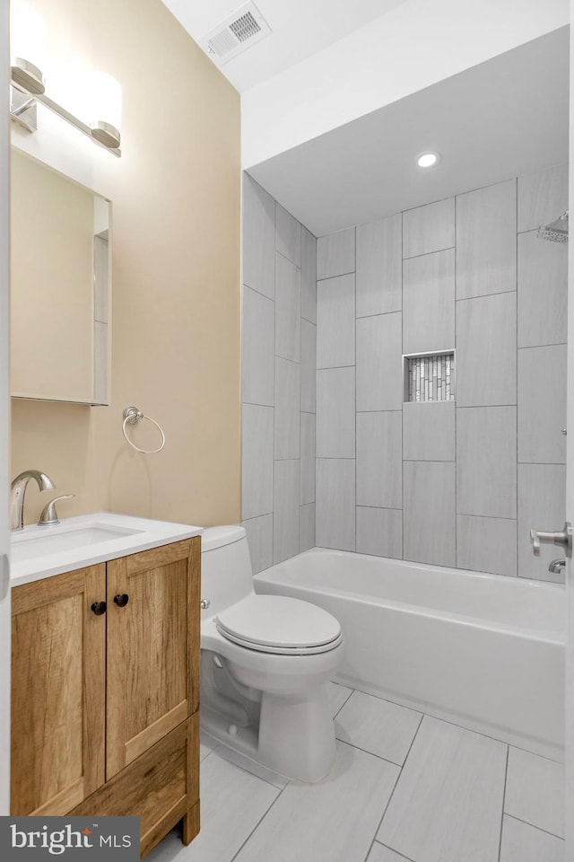 full bathroom featuring toilet, tiled shower / bath, vanity, and tile patterned floors