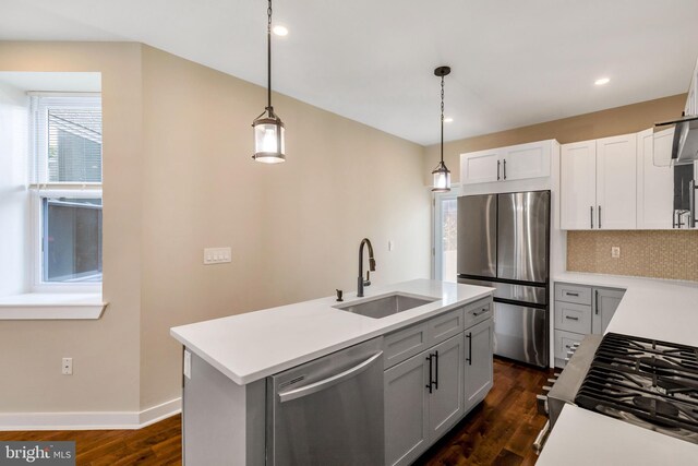 kitchen with sink, dark wood-type flooring, tasteful backsplash, stainless steel appliances, and a center island with sink