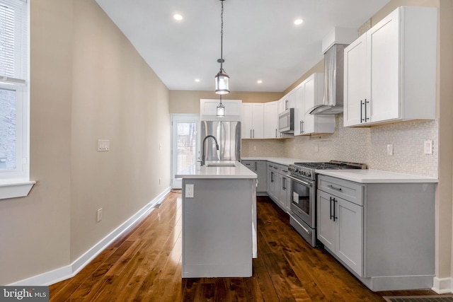 kitchen featuring appliances with stainless steel finishes, a center island with sink, dark hardwood / wood-style floors, and tasteful backsplash