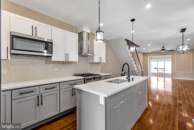 kitchen featuring appliances with stainless steel finishes, tasteful backsplash, wall chimney exhaust hood, and dark hardwood / wood-style floors