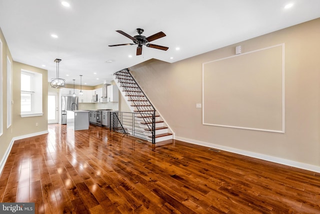 unfurnished living room with ceiling fan with notable chandelier and hardwood / wood-style floors