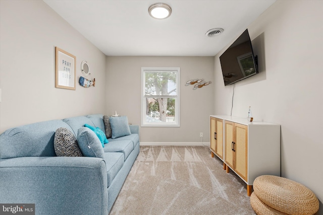 living area with baseboards, visible vents, and light carpet