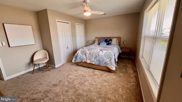 carpeted bedroom with ceiling fan and two closets