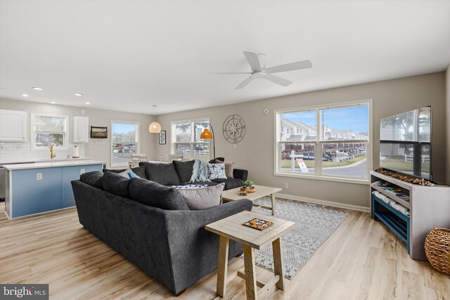 living area with recessed lighting, a ceiling fan, light wood-type flooring, and baseboards