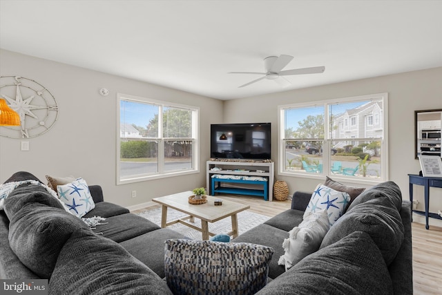 living area with ceiling fan, baseboards, a healthy amount of sunlight, and wood finished floors