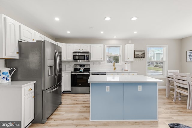 kitchen featuring appliances with stainless steel finishes, white cabinetry, a center island, and sink