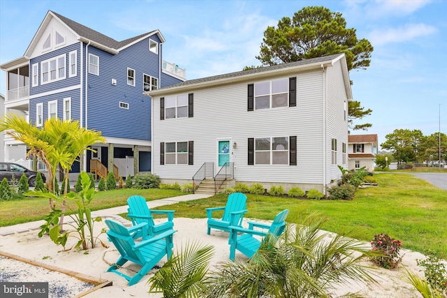 rear view of house with a patio, a lawn, and an outdoor fire pit