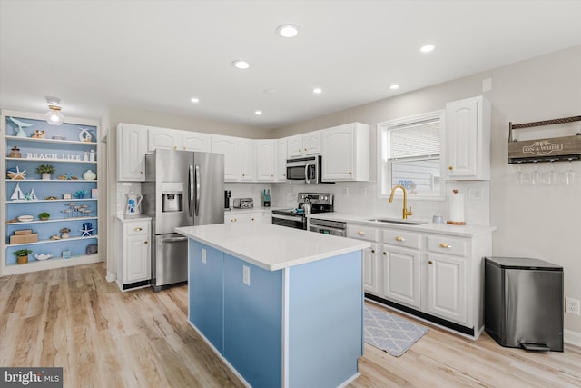 kitchen featuring light wood-style flooring, a sink, light countertops, white cabinets, and appliances with stainless steel finishes