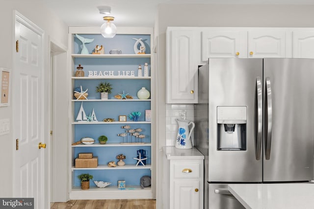 kitchen with white cabinetry, light countertops, wood finished floors, and stainless steel fridge