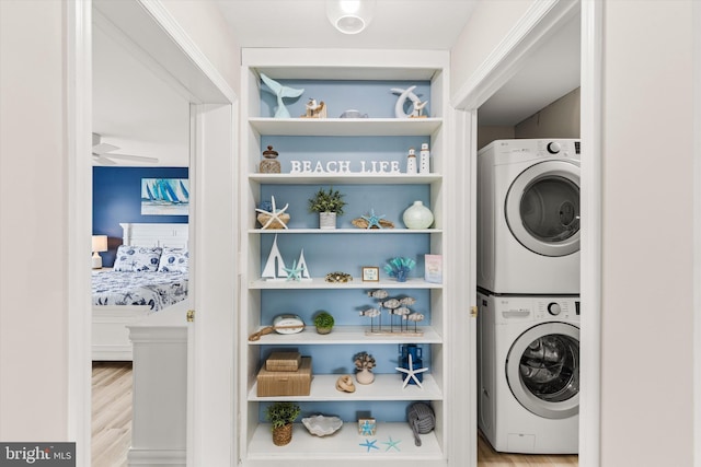 laundry area with stacked washer and dryer, wood finished floors, and laundry area