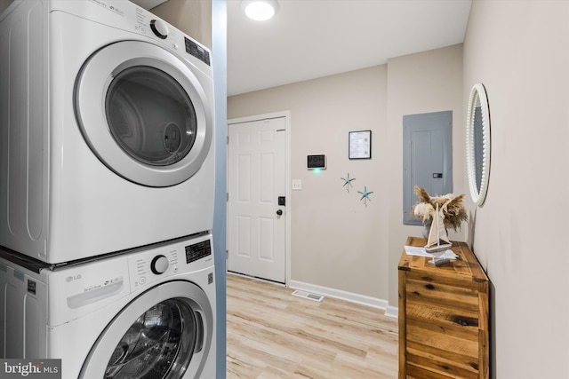 washroom featuring light hardwood / wood-style flooring, stacked washer / drying machine, and electric panel