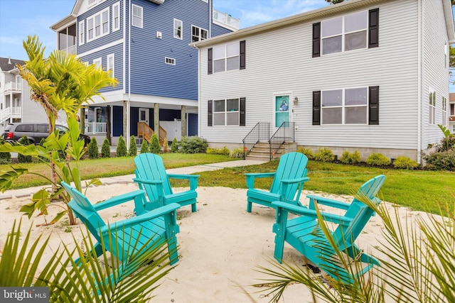 back of property with a yard, a fire pit, and a patio