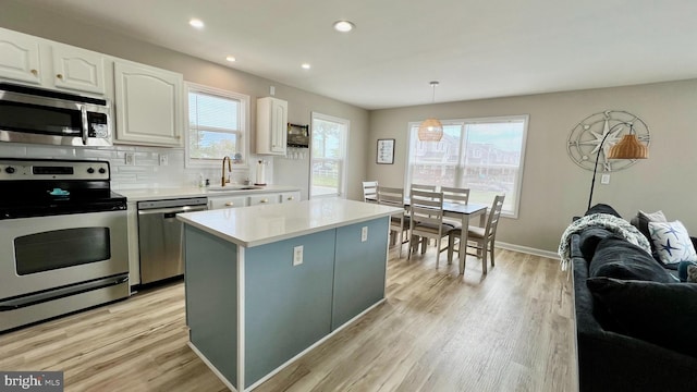 kitchen featuring white cabinetry, a center island, sink, appliances with stainless steel finishes, and light hardwood / wood-style floors