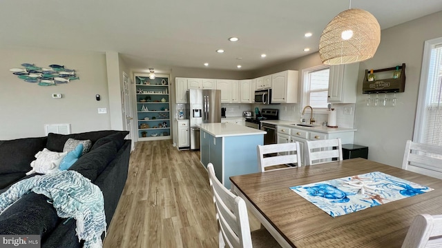 kitchen featuring pendant lighting, white cabinetry, a kitchen island, sink, and appliances with stainless steel finishes