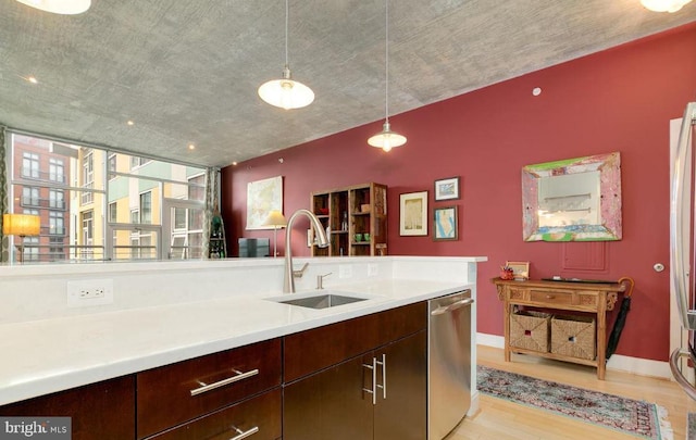 kitchen featuring pendant lighting, sink, stainless steel dishwasher, dark brown cabinets, and light hardwood / wood-style flooring