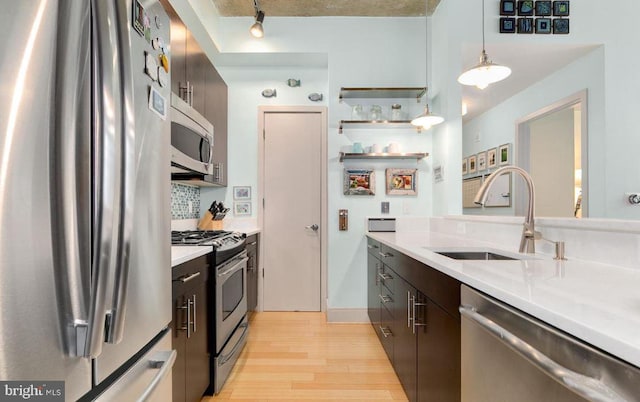 kitchen with light hardwood / wood-style flooring, appliances with stainless steel finishes, decorative light fixtures, and sink