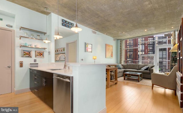 kitchen featuring dark brown cabinetry, sink, stainless steel dishwasher, decorative light fixtures, and light hardwood / wood-style flooring