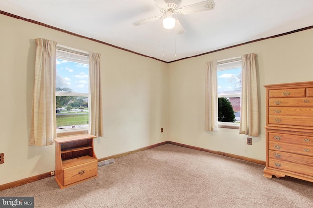 empty room featuring ornamental molding, ceiling fan, light colored carpet, and plenty of natural light