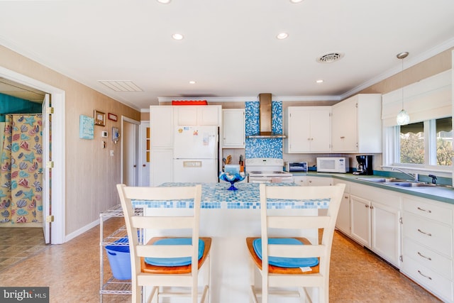 kitchen featuring decorative light fixtures, sink, wall chimney range hood, a kitchen island, and white appliances