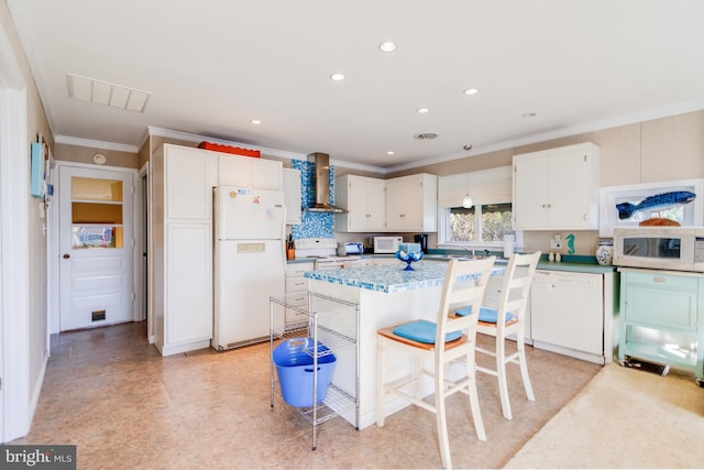 kitchen featuring white cabinetry, crown molding, wall chimney exhaust hood, and white appliances