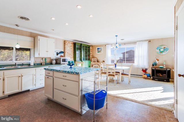 kitchen with sink, brick wall, tile patterned floors, pendant lighting, and white cabinets