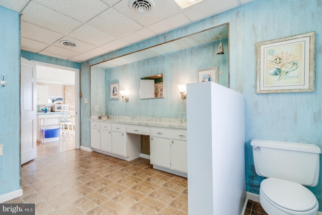 bathroom featuring a drop ceiling, toilet, tile patterned floors, and vanity