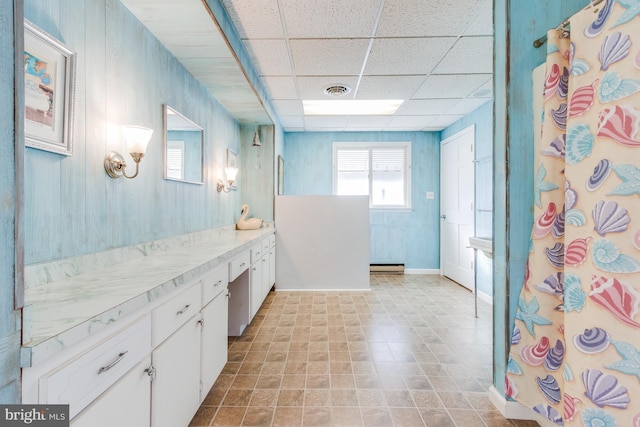 bathroom with a shower with shower curtain, baseboard heating, a drop ceiling, and vanity