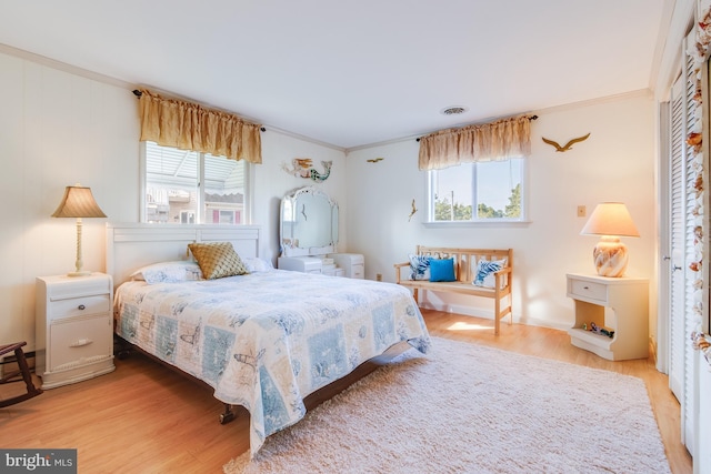 bedroom with light hardwood / wood-style flooring, crown molding, and multiple windows