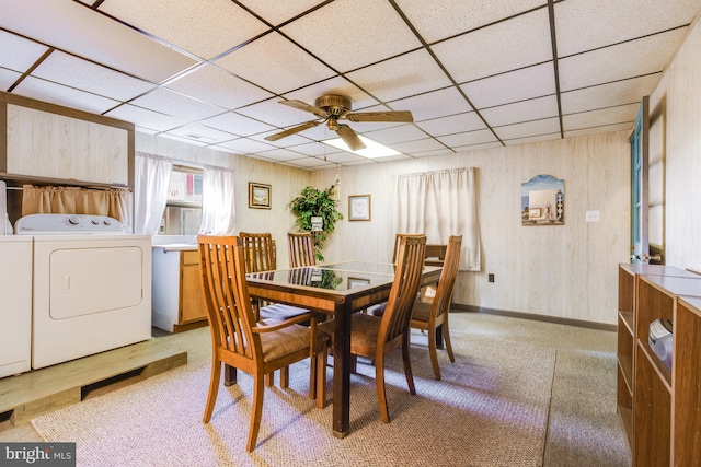 carpeted dining area featuring ceiling fan, washer and dryer, and a drop ceiling