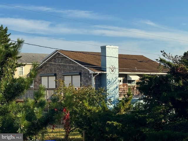 exterior space with a shingled roof and a chimney