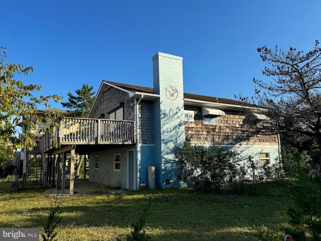 rear view of property with stairway, a chimney, a lawn, and a deck