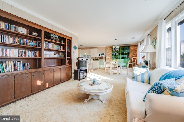 living room with a wealth of natural light, a notable chandelier, light colored carpet, and brick wall