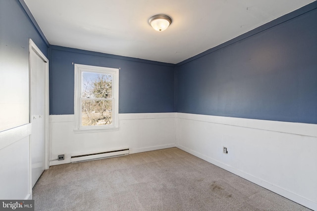 spare room featuring carpet flooring, a wainscoted wall, and a baseboard radiator