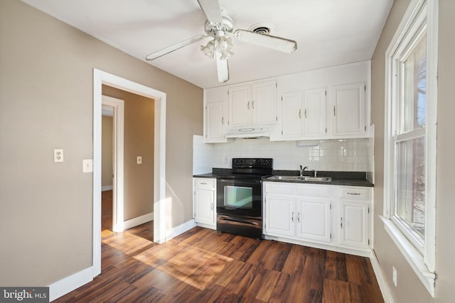 kitchen featuring dark countertops, under cabinet range hood, electric range, white cabinets, and a sink