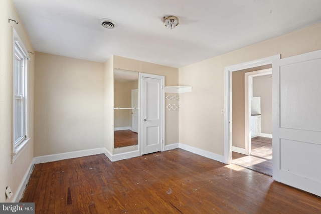 unfurnished bedroom featuring a closet, baseboards, visible vents, and wood-type flooring