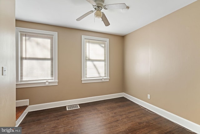 empty room featuring visible vents, ceiling fan, baseboards, and dark wood-style flooring