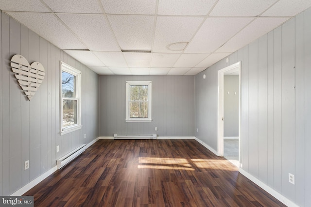 unfurnished room with a baseboard radiator, a paneled ceiling, dark wood-type flooring, and baseboards