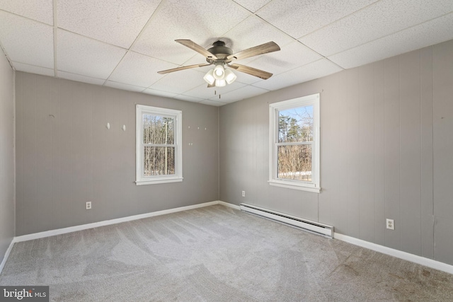 carpeted spare room with baseboard heating, baseboards, ceiling fan, and a drop ceiling