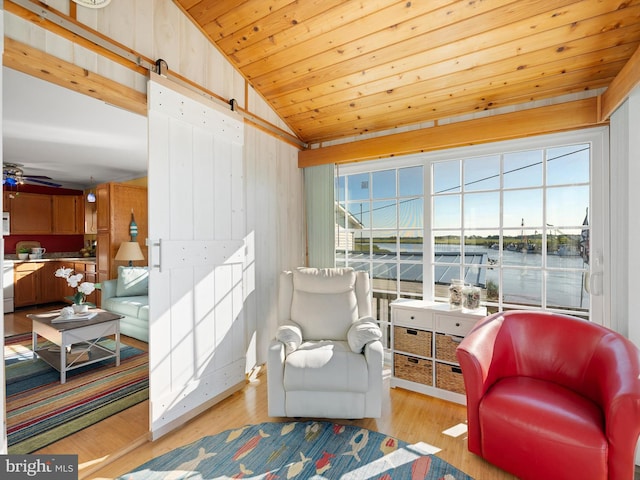 sitting room with light wood-type flooring, lofted ceiling, plenty of natural light, and wooden walls