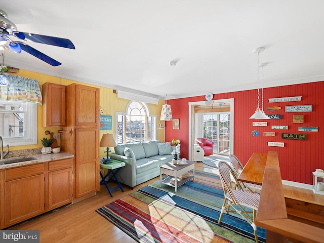 living room featuring a wealth of natural light, light hardwood / wood-style flooring, sink, and ceiling fan