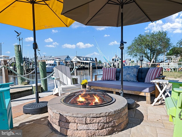 view of patio / terrace with a water view, a boat dock, and an outdoor fire pit